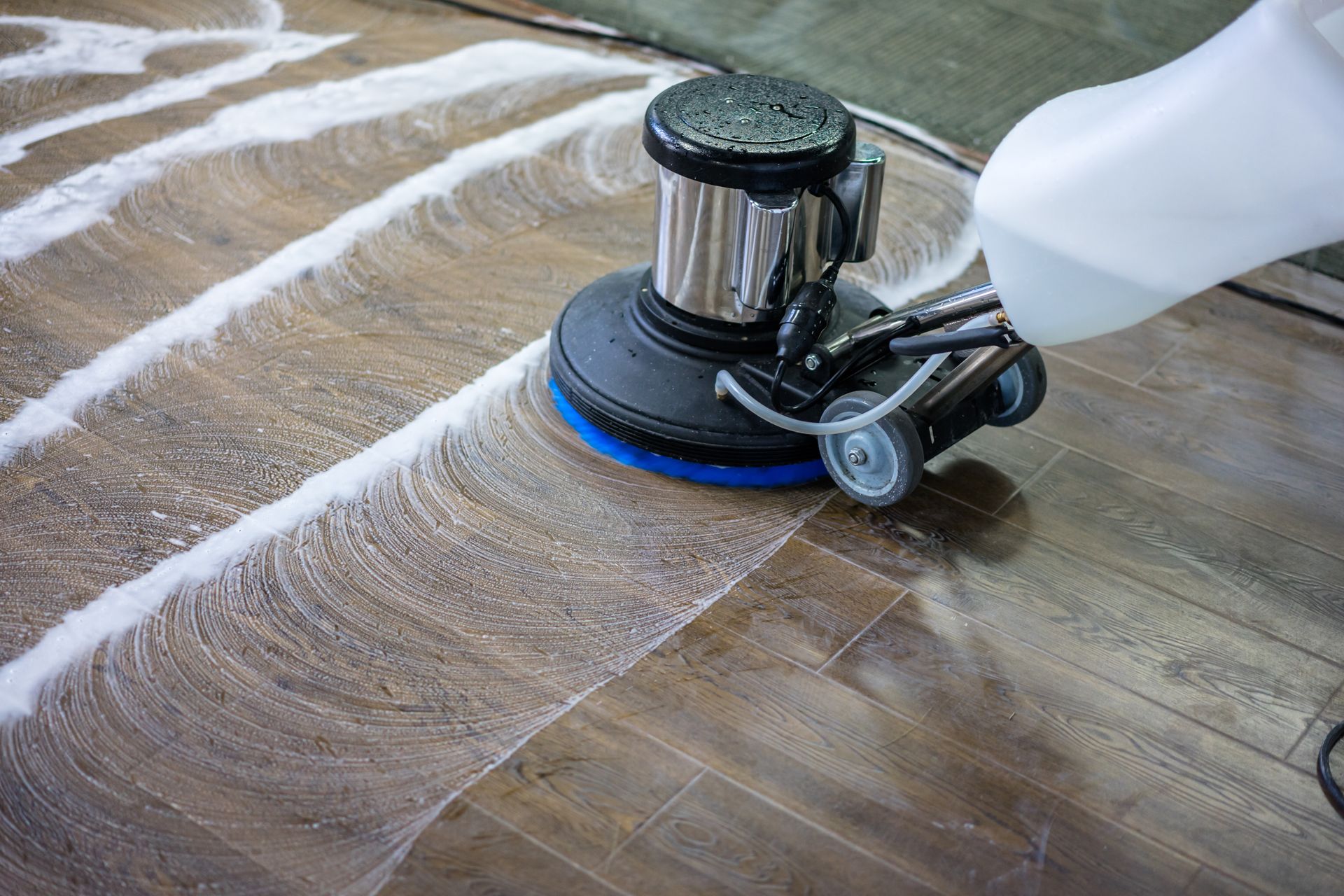 Floor cleaning machine scrubbing a hardwood floor with foamy cleaning solution. Floor cleaning machine scrubbing a hardwood floor with foamy cleaning solution.