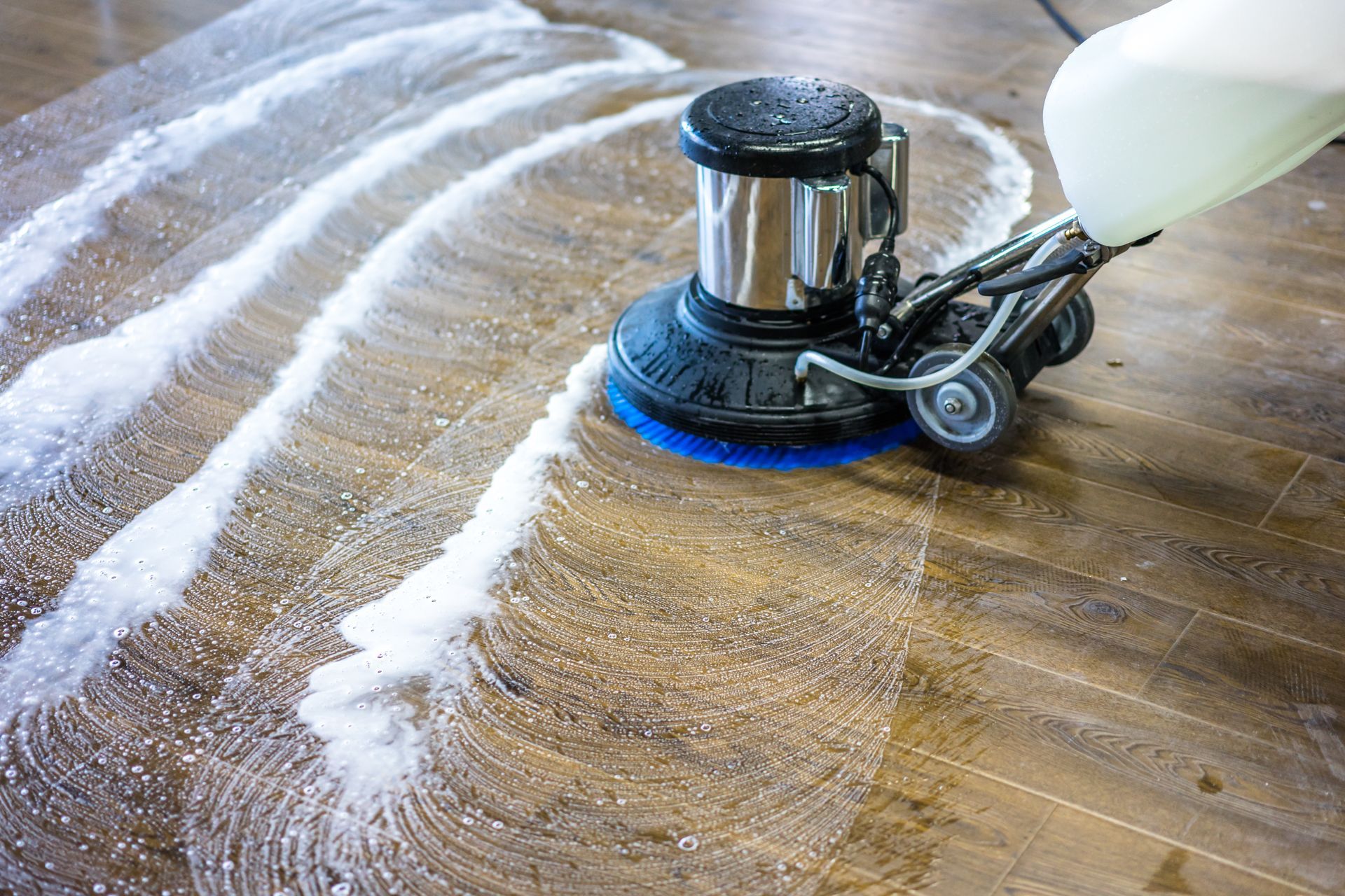 Floor cleaning machine scrubbing a wood floor, leaving soapy white trails. Floor cleaning machine scrubbing a wood floor, leaving soapy white trails.