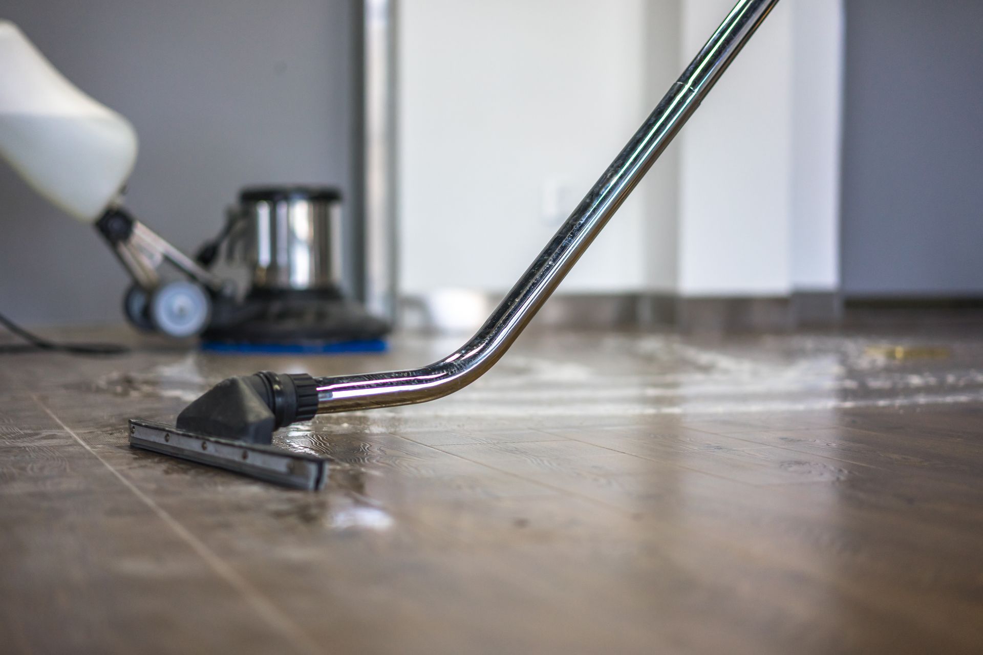 Floor cleaning machine with nozzle spraying liquid, on a wet, tiled floor in a room. Floor cleaning machine with nozzle spraying liquid, on a wet, tiled floor in a room.