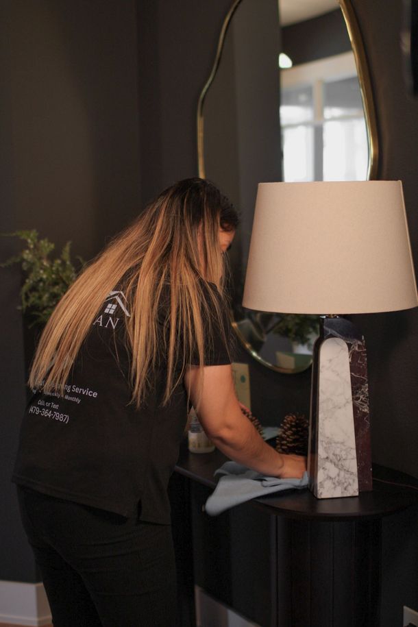 Person mopping a wooden floor, wearing yellow gloves and blue overalls, boxes in the background.