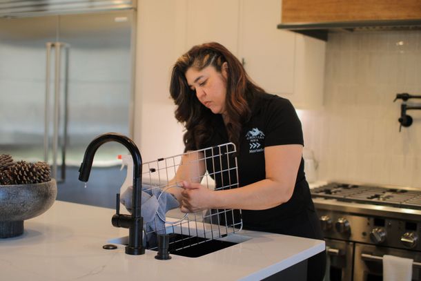 Floor cleaning machine scrubbing a wood floor, leaving soapy white trails.