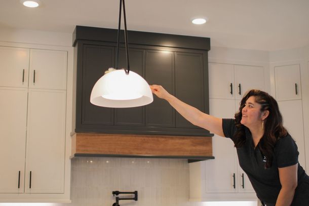 Hands in orange gloves spraying cleaner on a kitchen countertop with a pink cloth.