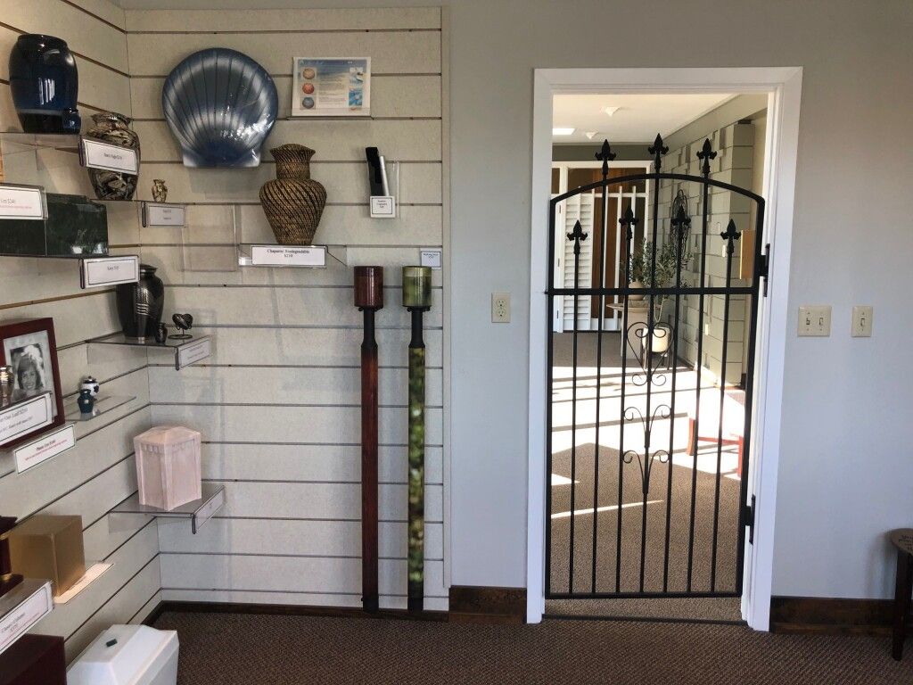 Display of urns and a gated doorway in an interior room. Shelves hold various urn styles.