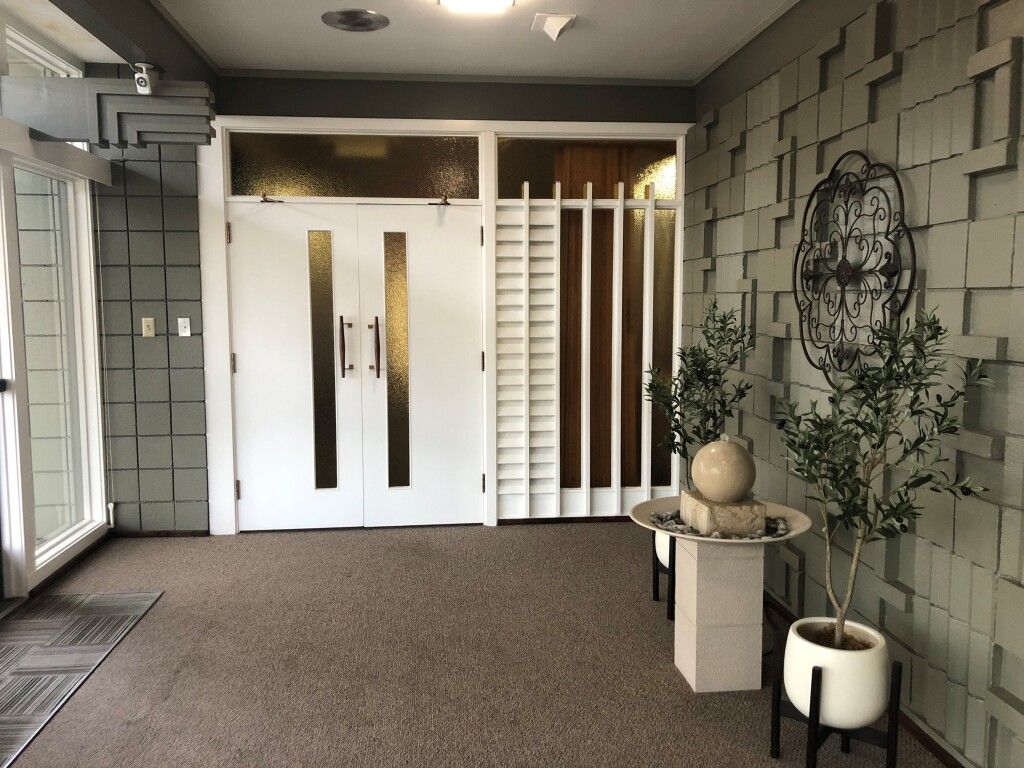Interior entrance with textured gray walls, white doors, and a small table with plants.