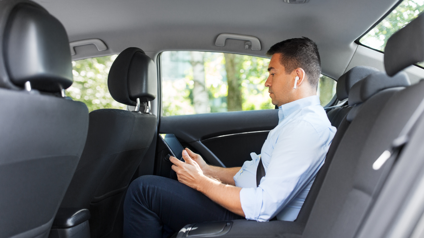 Interior of a limousine with black leather seats, a bar, and overhead lighting.