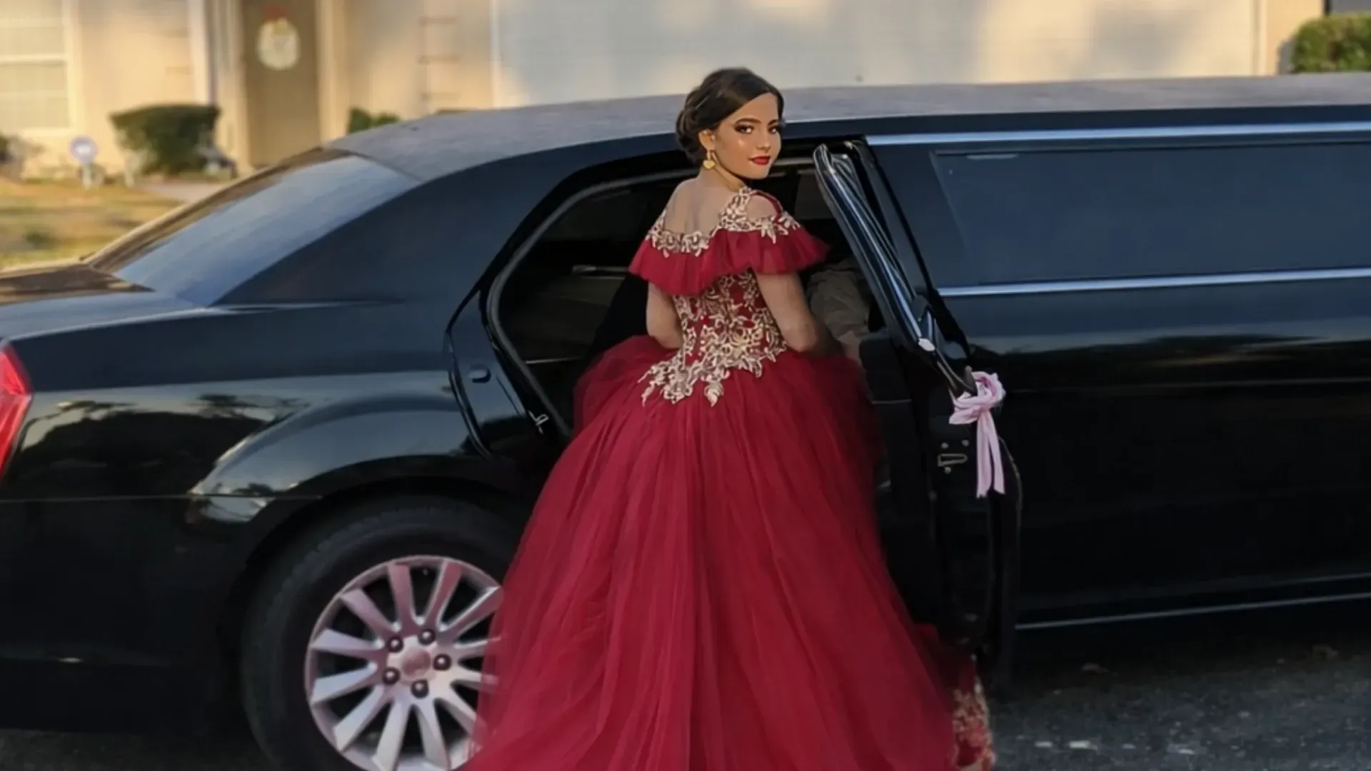 Woman in red gown exiting a black limousine.