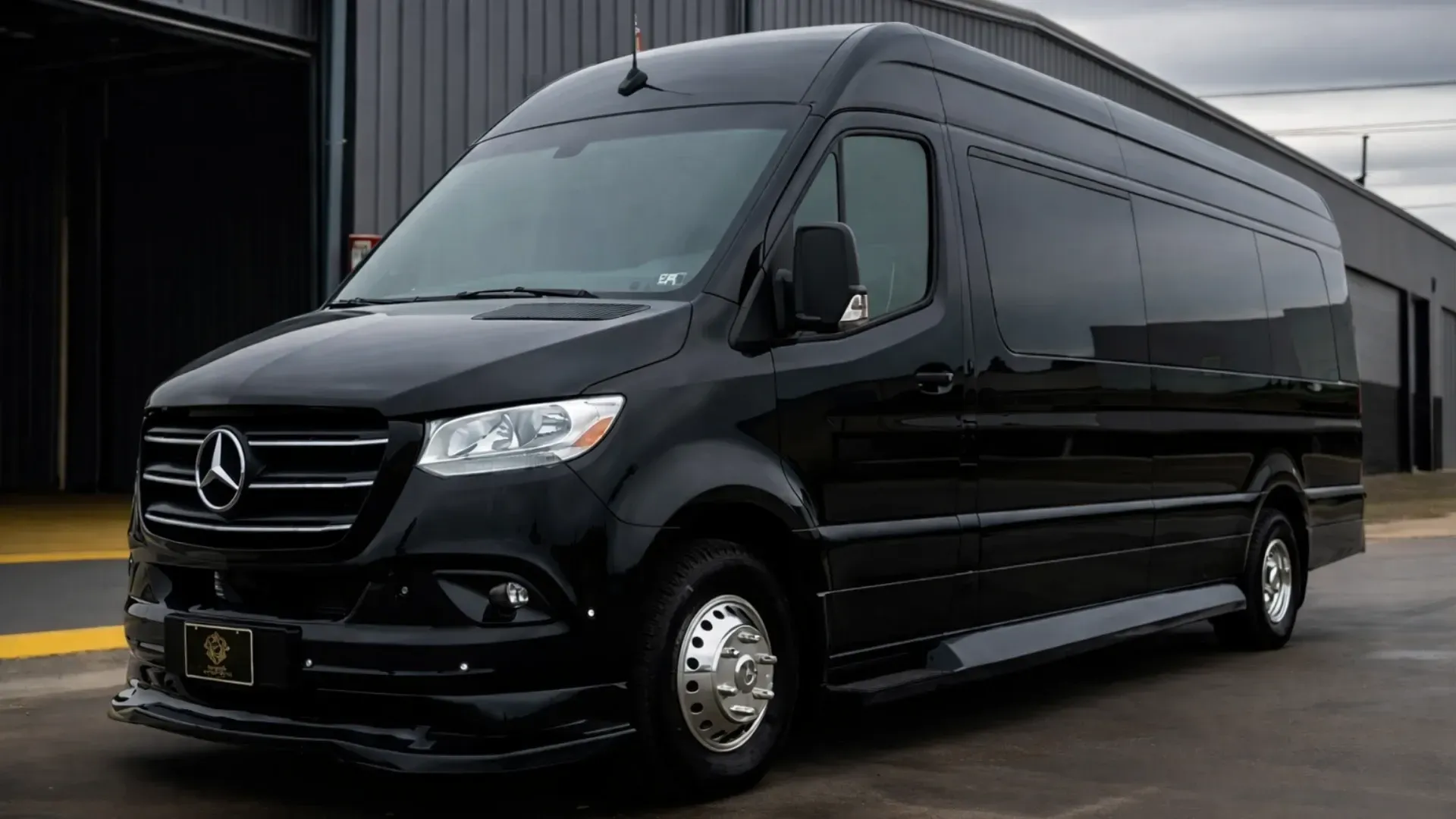 Black Mercedes-Benz Sprinter van parked in front of a modern building.