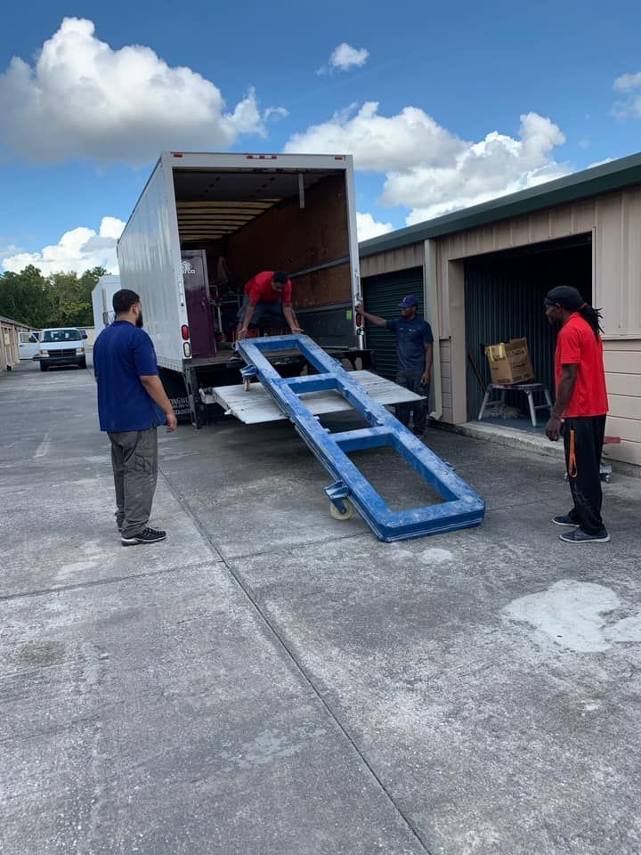 A group of men are loading a truck with a ramp.