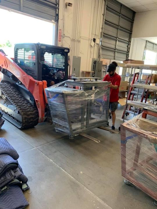 A man is standing next to a bulldozer in a warehouse. 28.4845° N, 81.2519° W