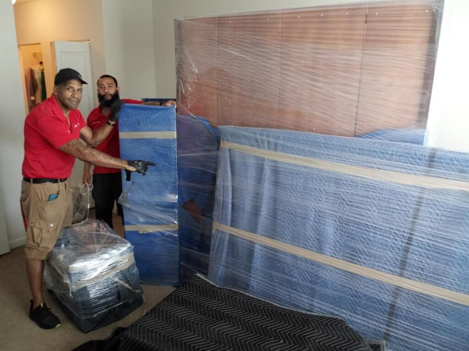 Two men are standing next to each other in a room wrapped in plastic.