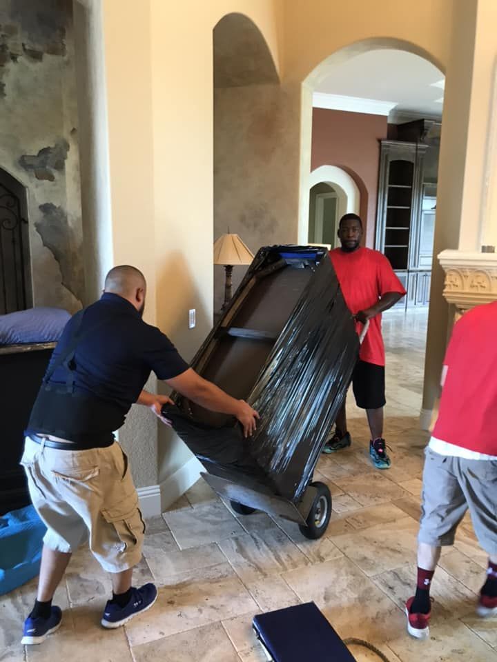 A man is pushing a couch on a cart in a living room.