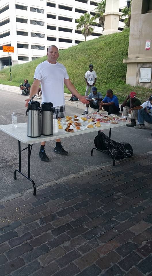 A man is standing in front of a table with food on it.