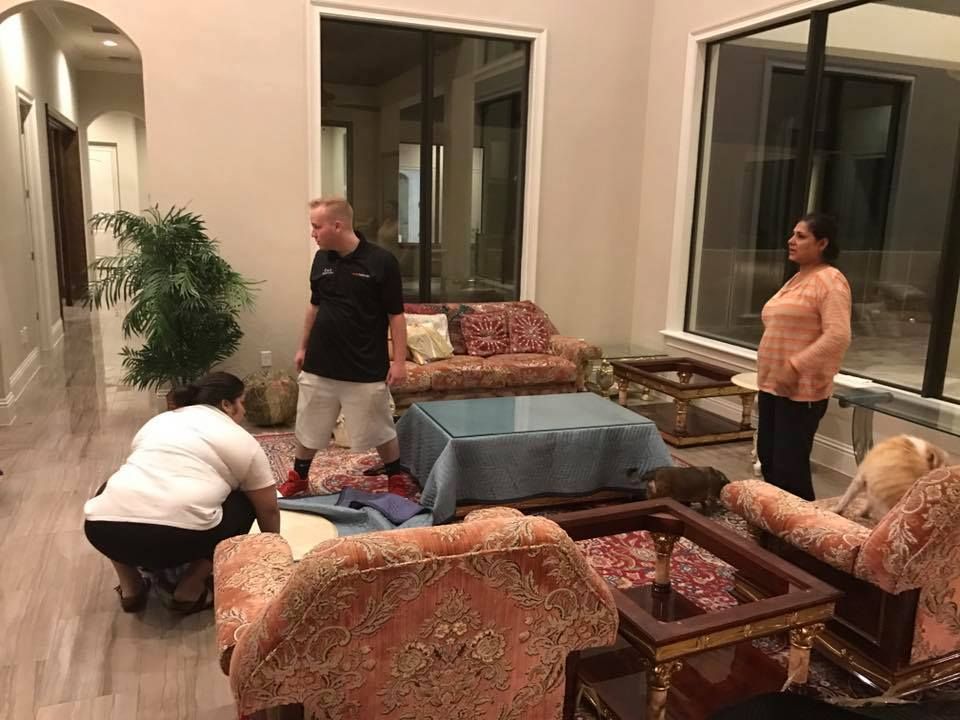 A group of people are moving furniture in a living room.