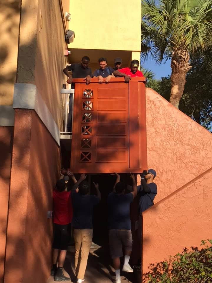 A group of people are lifting a wooden box into a building.