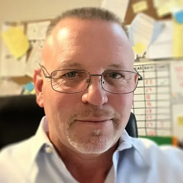 A man wearing glasses and a white shirt is sitting in a chair. 28.4845° N, 81.2519° W