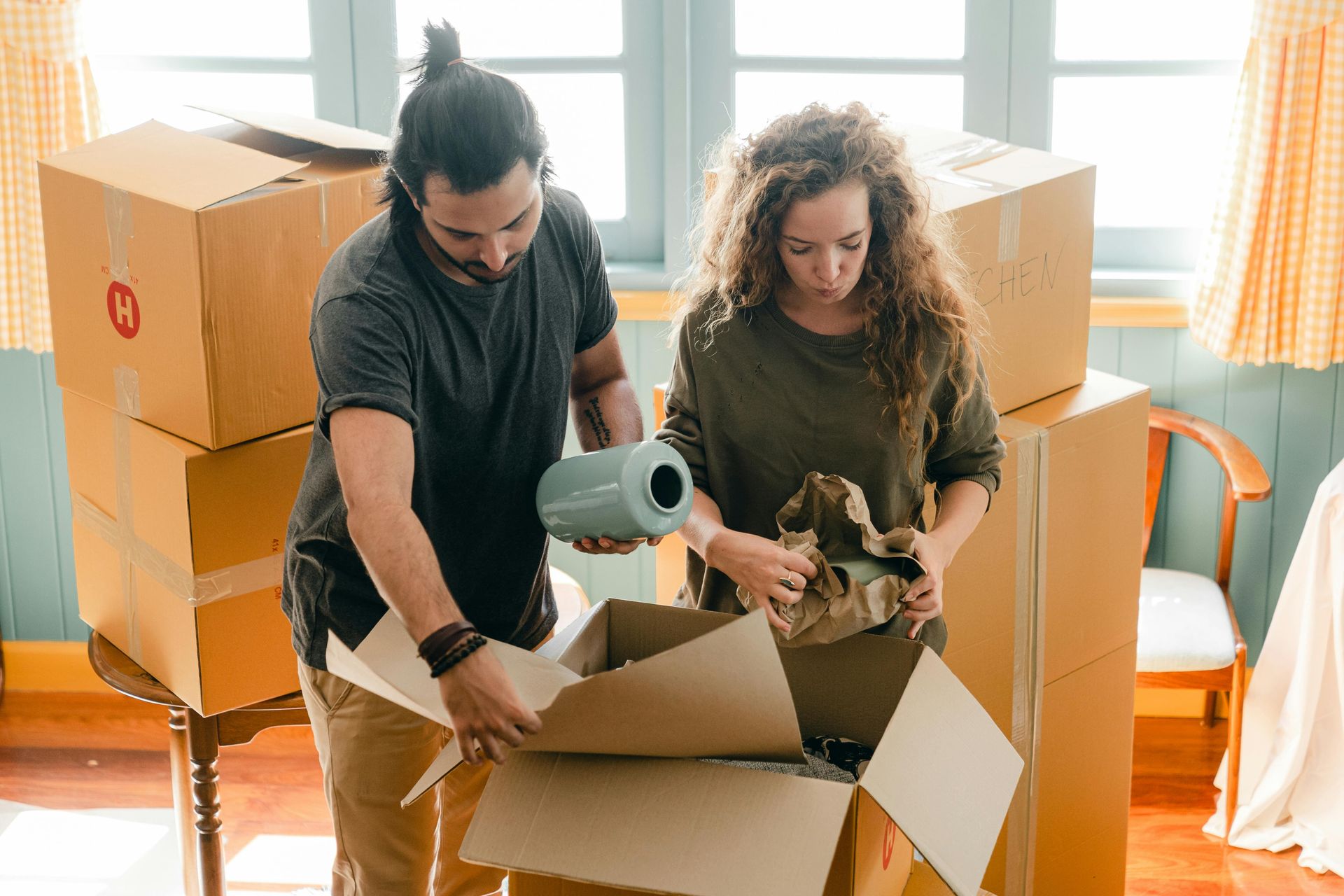 A man and a woman are packing boxes in a room.