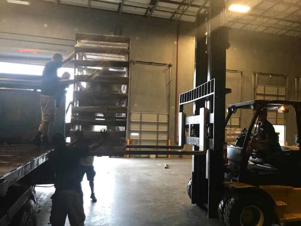 A forklift is moving a large stack of shelves in a warehouse. 28.4845° N, 81.2519° W