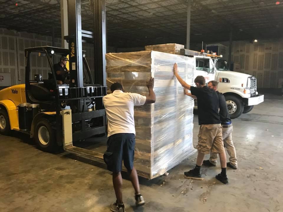 A forklift is lifting a large pallet in a warehouse. 28.4845° N, 81.2519° W