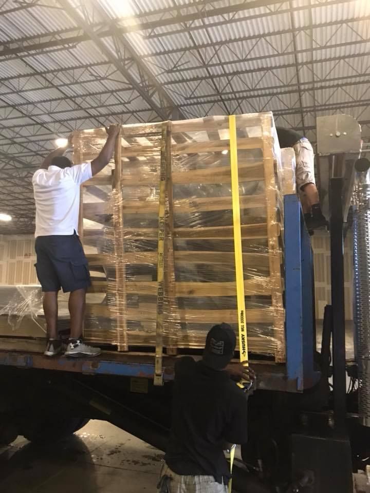 Two men are loading pallets onto a truck in a warehouse 28.4845° N, 81.2519° W