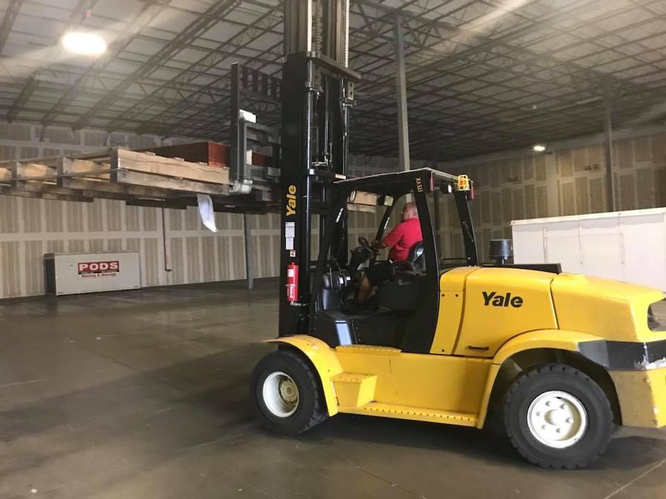 A man is driving a yellow forklift in a warehouse. 28.4845° N, 81.2519° W