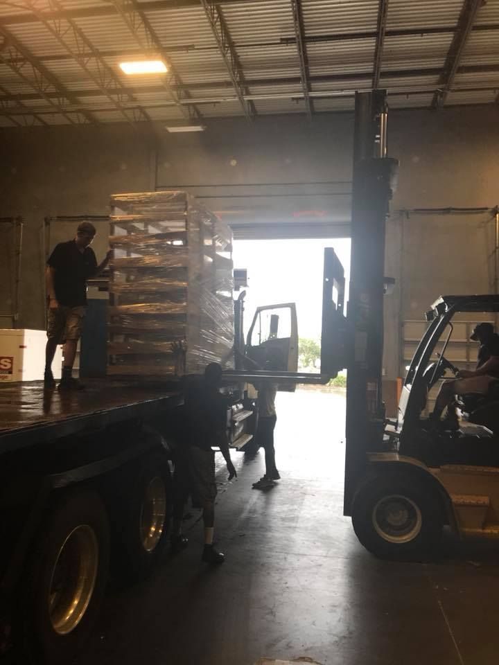 A forklift is loading pallets onto a truck in a warehouse. 28.4845° N, 81.2519° W