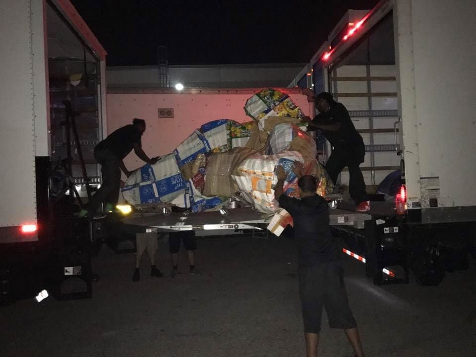 A group of people are loading a large truck at night 28.4845° N, 81.2519° W