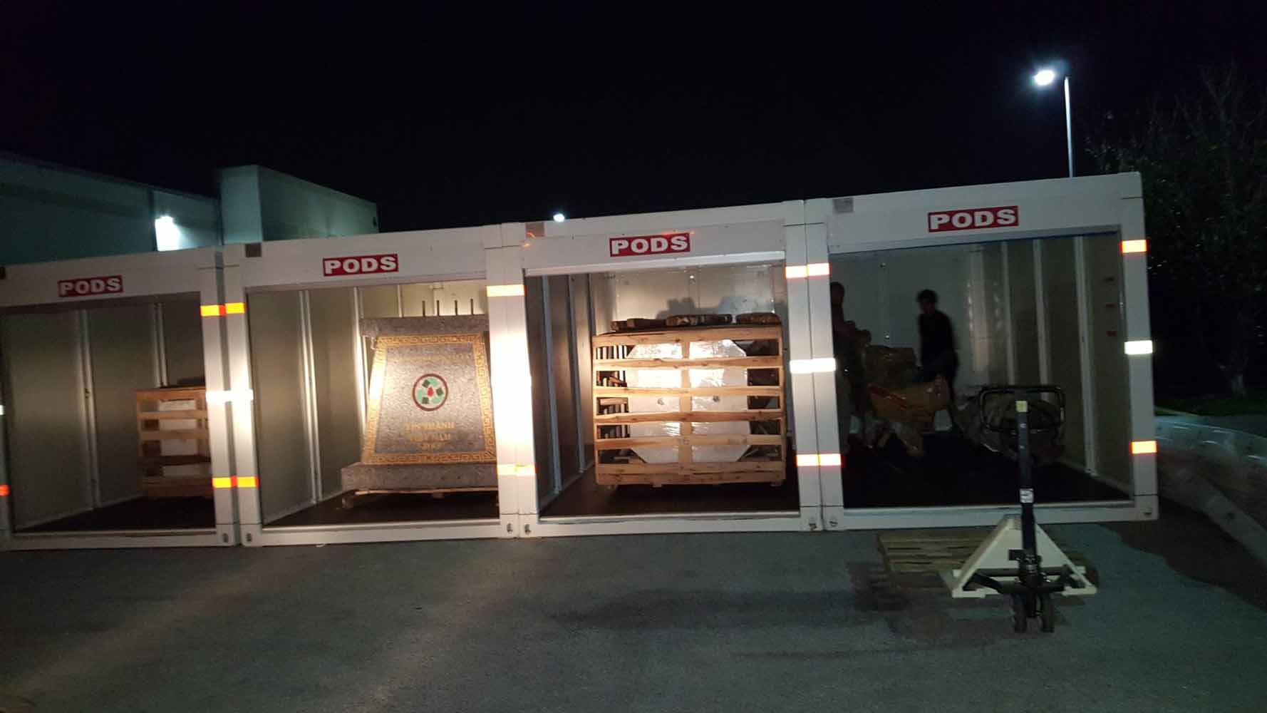 A group of containers filled with pallets are sitting in a parking lot at night. 28.4845° N, 81.2519° W