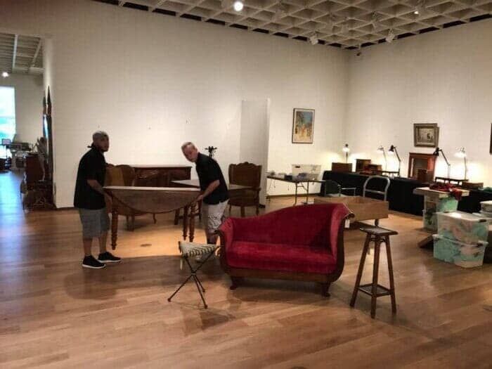 Two men are moving a red couch in a large room 28.4845° N, 81.2519° W