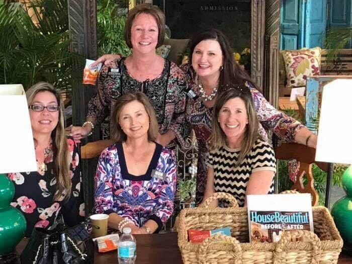 A group of women are posing for a picture while sitting at a table. 28.4845° N, 81.2519° W