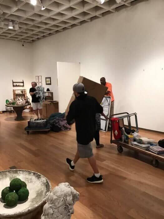 A man is carrying a large cardboard box in a room. 28.4845° N, 81.2519° W