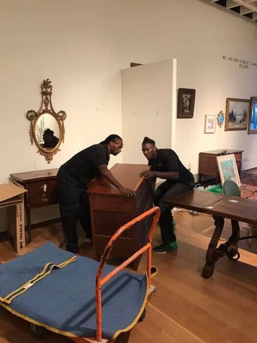Two men are moving a dresser in a living room 28.4845° N, 81.2519° W