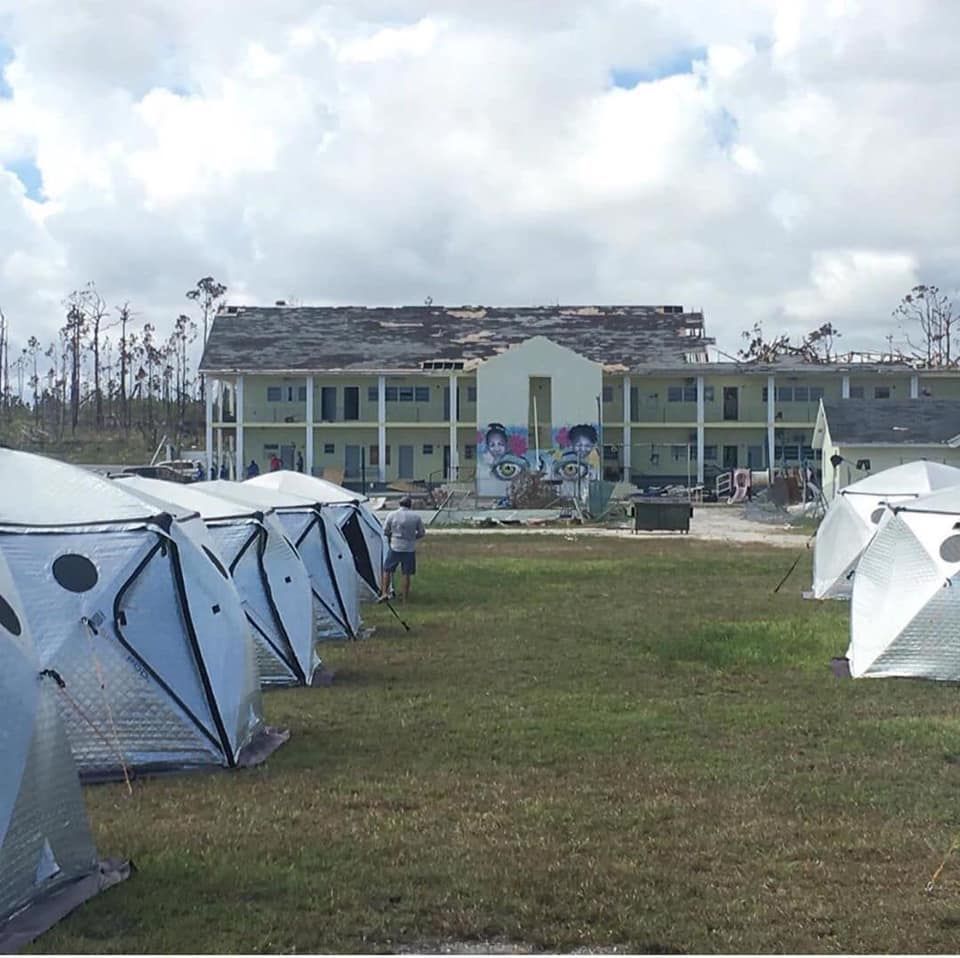A group of tents are lined up in front of a large building 28.4845° N, 81.2519° W