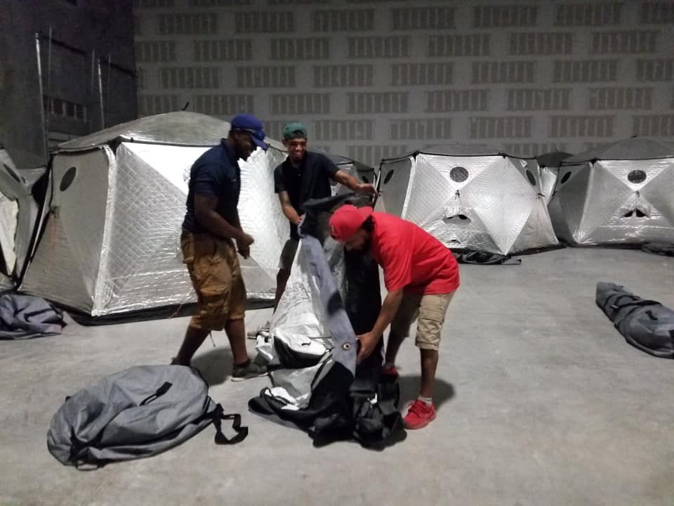 A group of men are setting up tents in a warehouse 28.4845° N, 81.2519° W