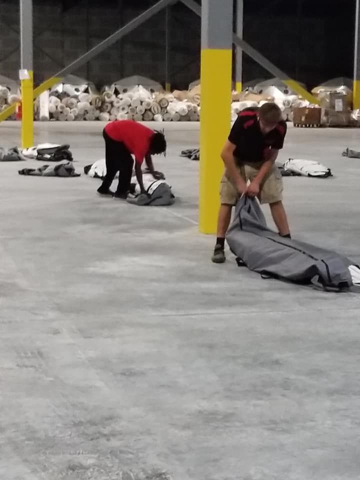 A man in a red shirt is kneeling down in a warehouse 28.4845° N, 81.2519° W