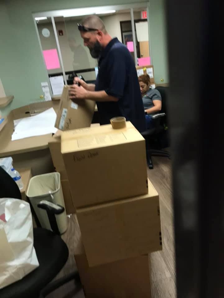 A man is working on a stack of cardboard boxes in an office 28.4845° N, 81.2519° W