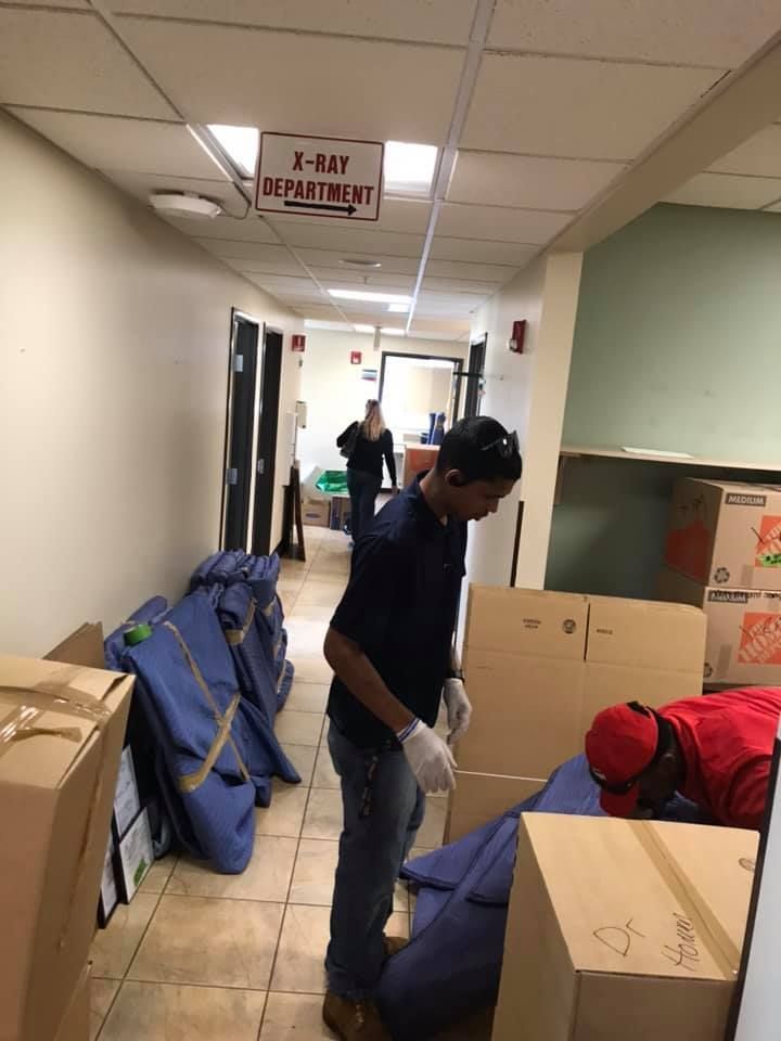 A man is standing in a hallway with boxes under a sign that says x-ray adjustment 28.4845° N, 81.2519° W