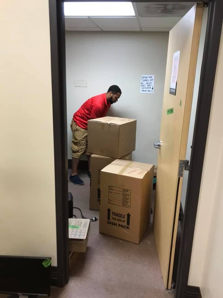 A man in a red shirt is moving boxes in a room 28.4845° N, 81.2519° W