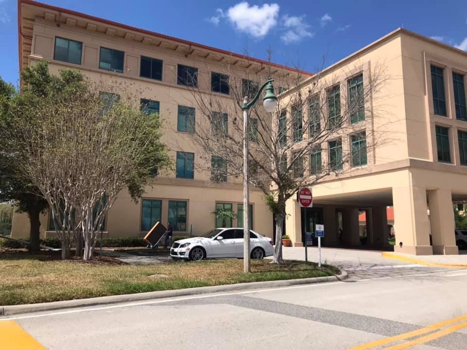 A white car is parked in front of a large building. 28.4845° N, 81.2519° W