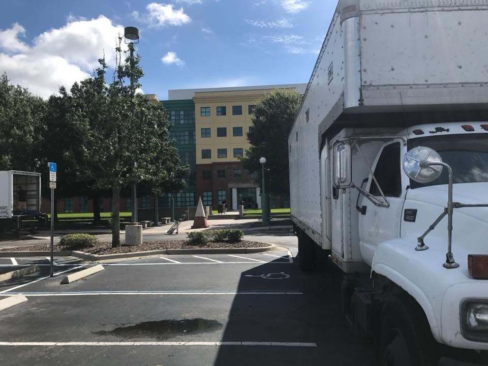 A white truck is parked in a parking lot in front of a building 28.4845° N, 81.2519° W