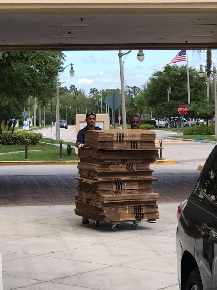 A man is pushing a cart full of cardboard boxes 28.4845° N, 81.2519° W
