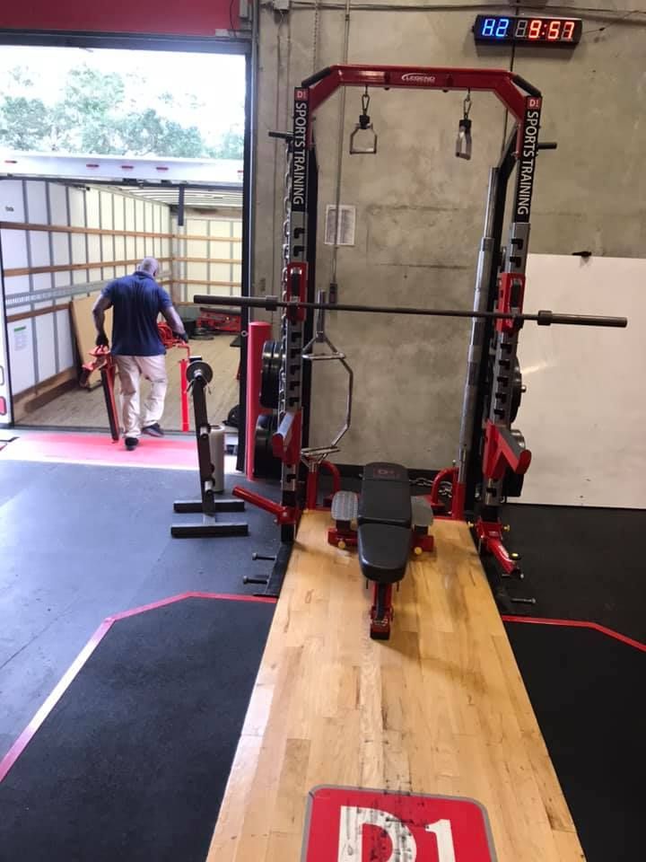 A man in a blue shirt is standing in a gym with a red sign that says d1 28.4845° N, 81.2519° W
