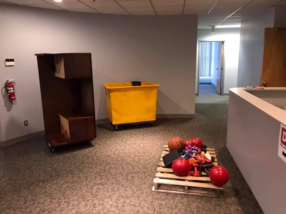 A room with a wooden pallet filled with toys and a yellow bin. 28.4845° N, 81.2519° W