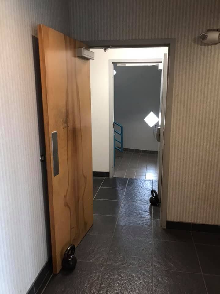 A hallway with a wooden door and a tiled floor. 28.4845° N, 81.2519° W