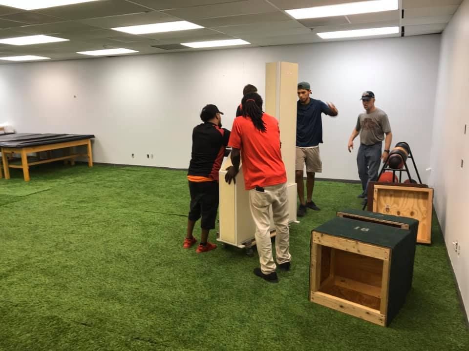 A group of people are moving a piece of furniture in a room. 28.4845° N, 81.2519° W