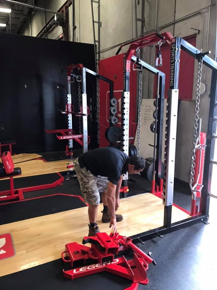 A man is working on a machine in a gym. 28.4845° N, 81.2519° W