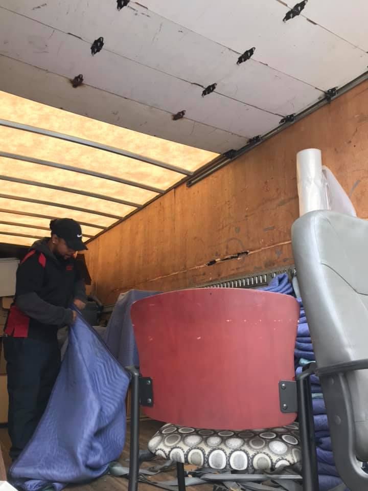 A man is loading chairs into a moving truck. 28.4845° N, 81.2519° W