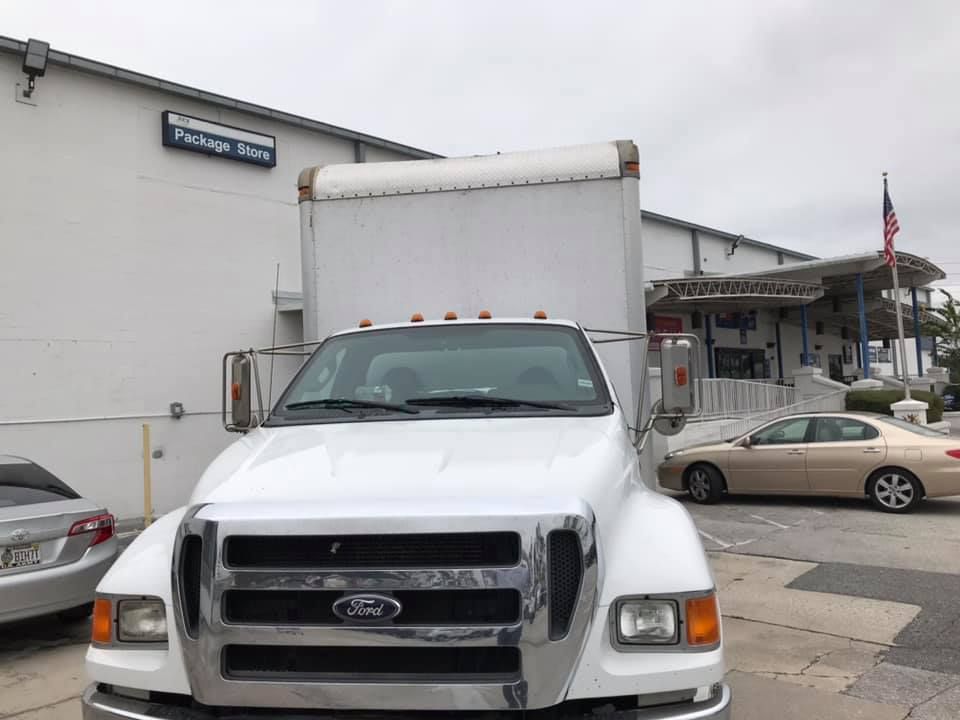 A white ford truck is parked in front of a building. 28.4845° N, 81.2519° W