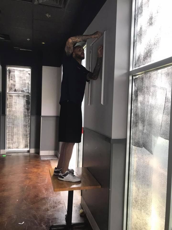 A man is standing on a table in front of a window 28.4845° N, 81.2519° W