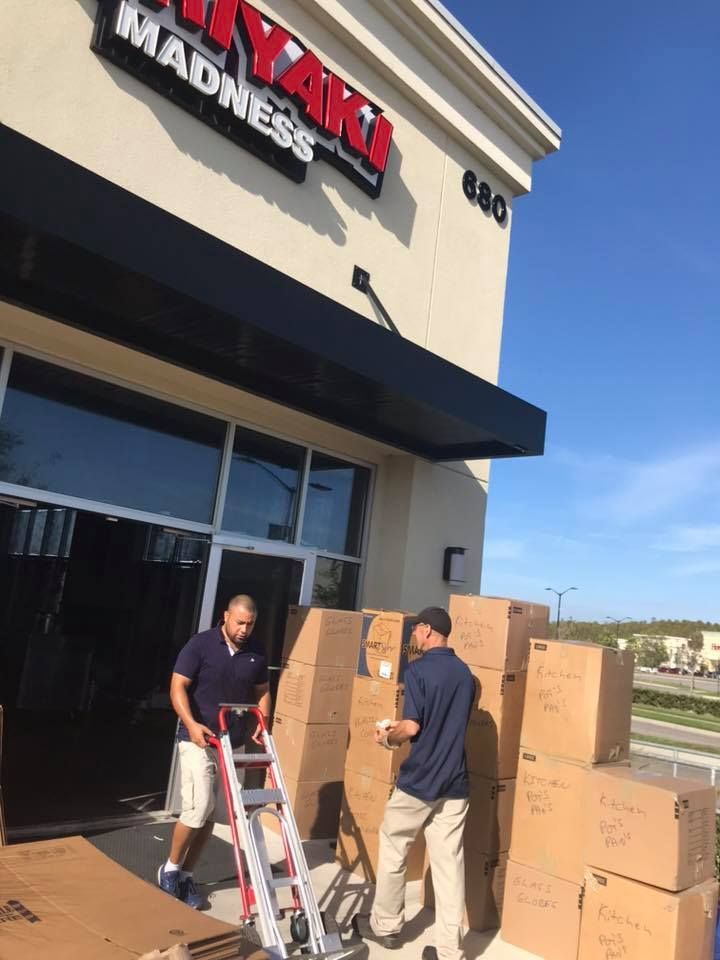 Two men are standing in front of a building that says madness 28.4845° N, 81.2519° W