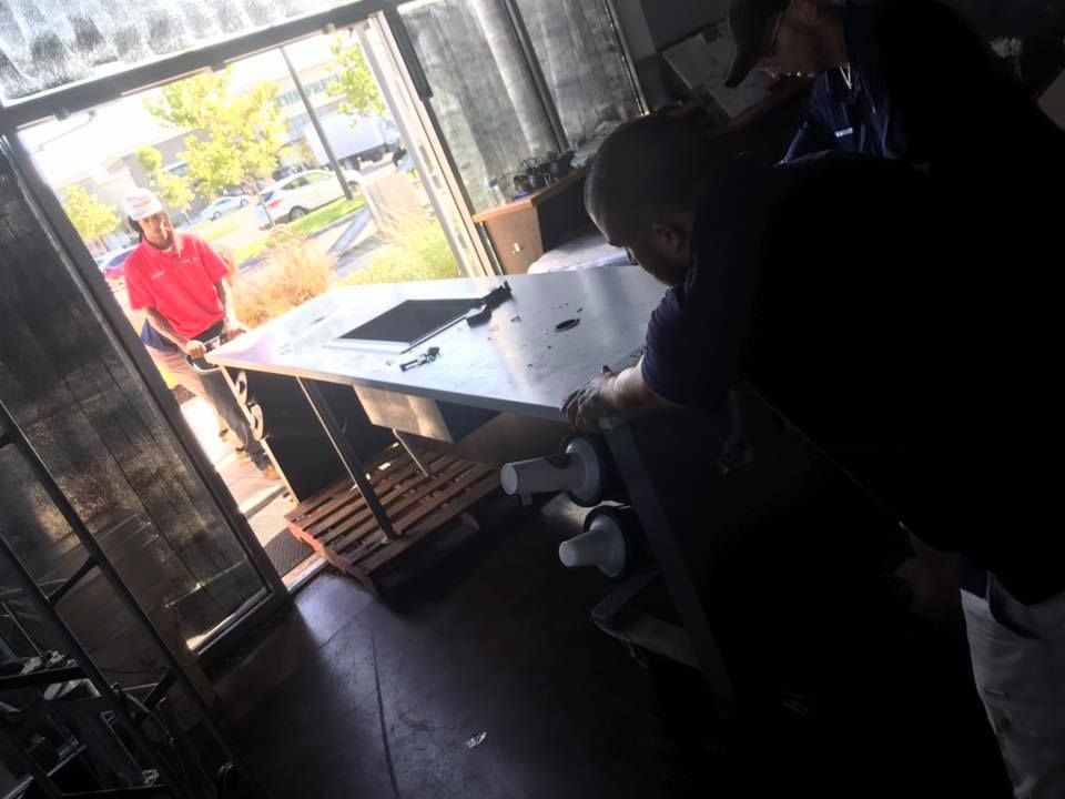 A man in a red shirt is standing behind a counter in a kitchen. 28.4845° N, 81.2519° W